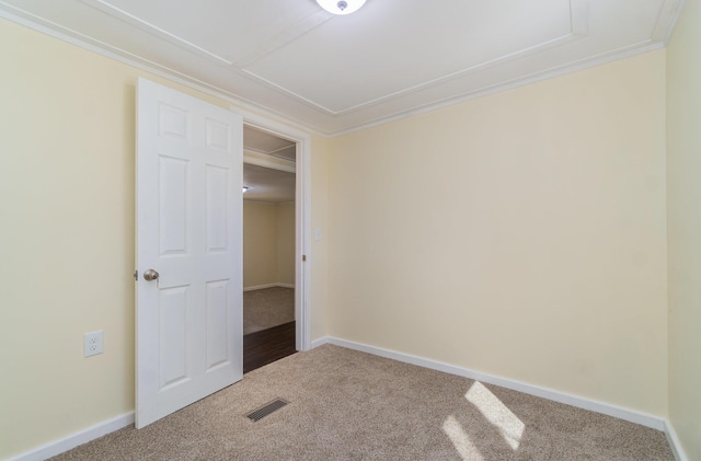 carpeted spare room with visible vents, baseboards, and crown molding