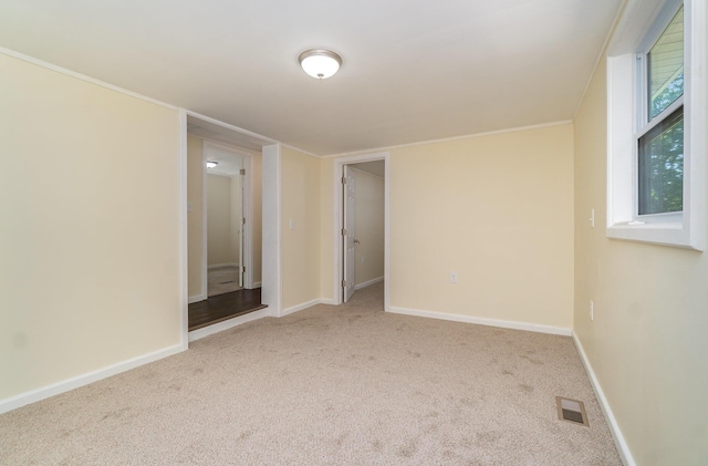 spare room featuring visible vents, baseboards, ornamental molding, and carpet flooring