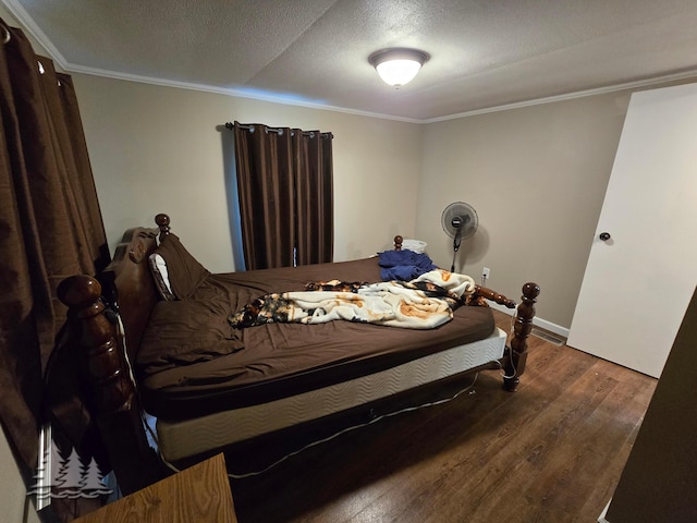 bedroom with ornamental molding, a textured ceiling, baseboards, and wood finished floors