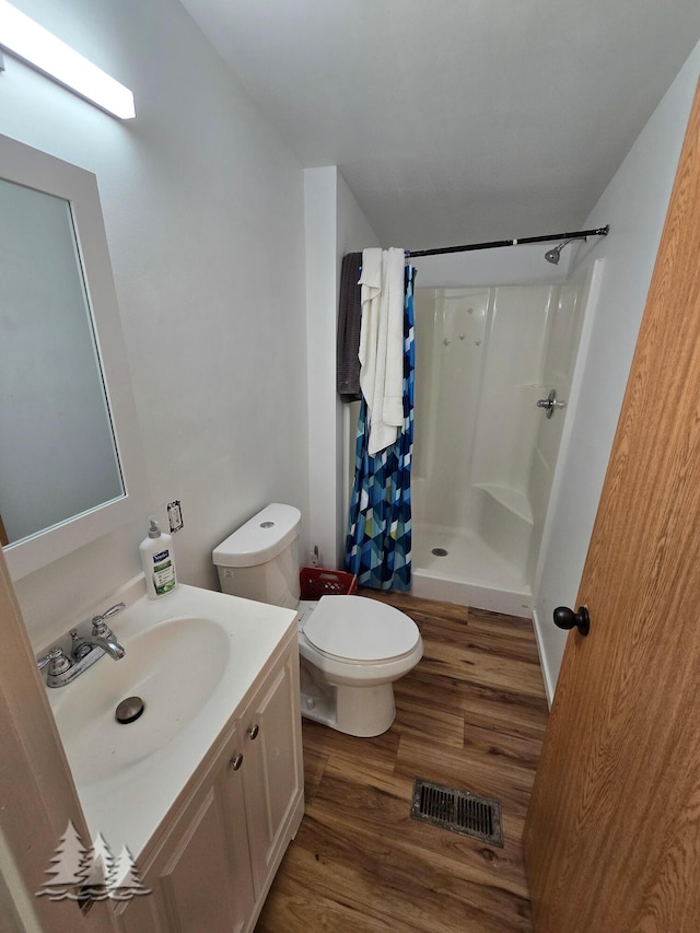 bathroom featuring visible vents, toilet, a stall shower, wood finished floors, and vanity