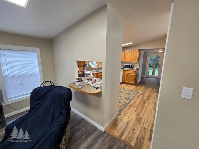 interior space with light wood-style flooring, baseboards, lofted ceiling, and a sink