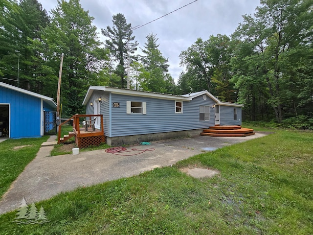 rear view of house with a yard, an outbuilding, and a deck