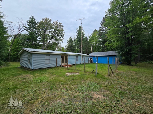 rear view of house with metal roof and a yard