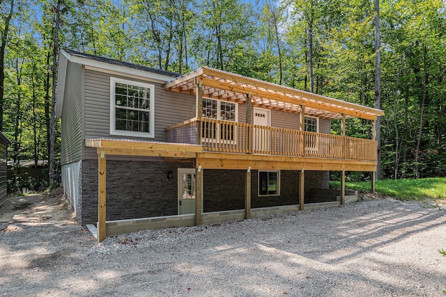 view of front of property with stone siding, driveway, and a wooden deck