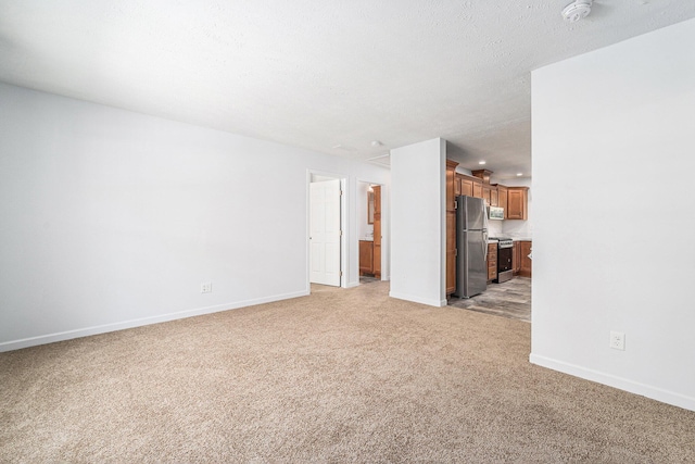 unfurnished living room with light carpet, a textured ceiling, and baseboards