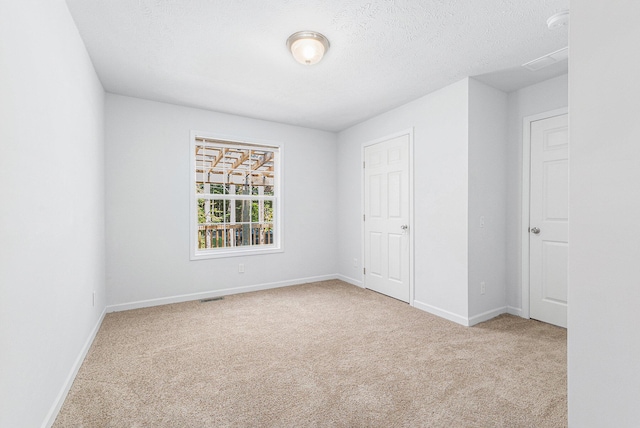 spare room featuring visible vents, baseboards, a textured ceiling, and carpet flooring