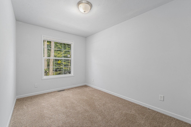 carpeted empty room featuring visible vents, baseboards, and a textured ceiling