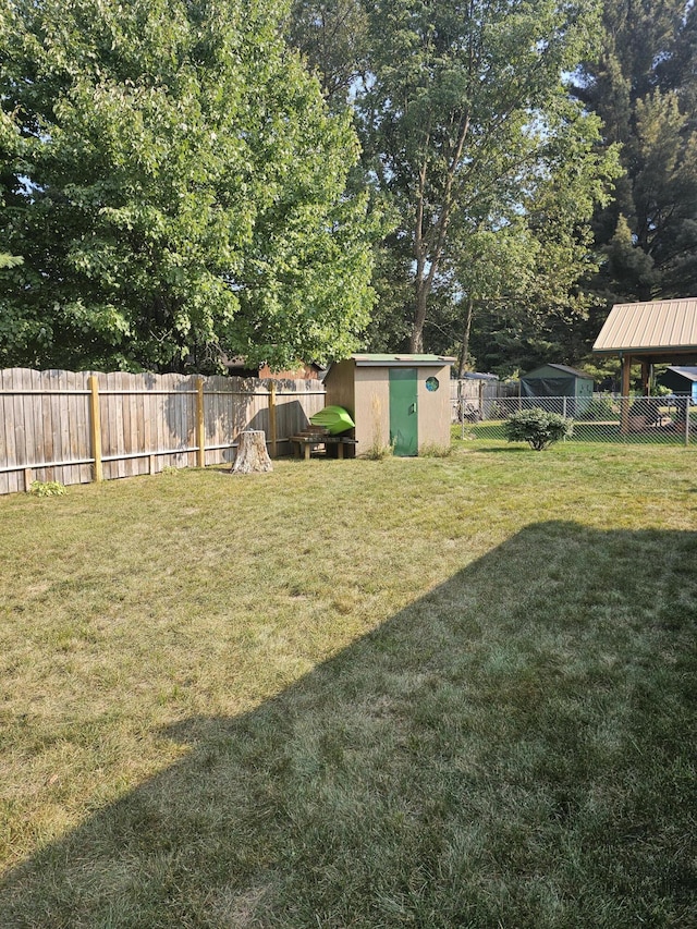 view of yard featuring a storage shed, an outdoor structure, and a fenced backyard