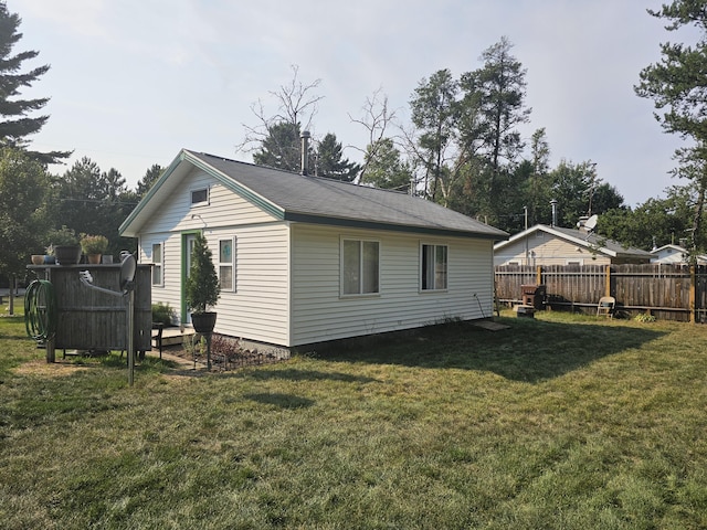 rear view of house featuring a yard and fence