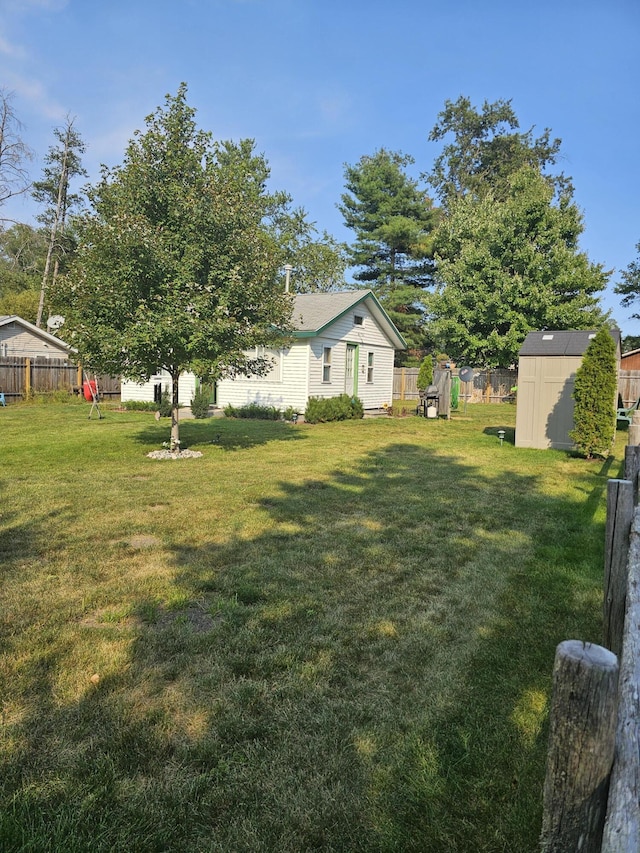 view of yard with an outbuilding, a storage unit, and a fenced backyard