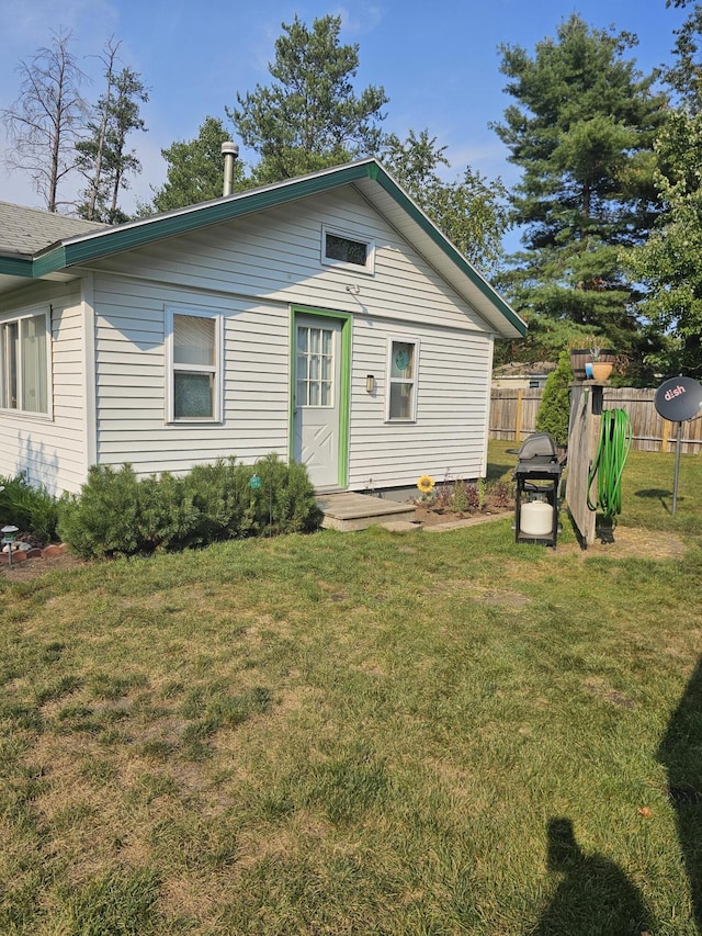 rear view of house featuring fence and a lawn