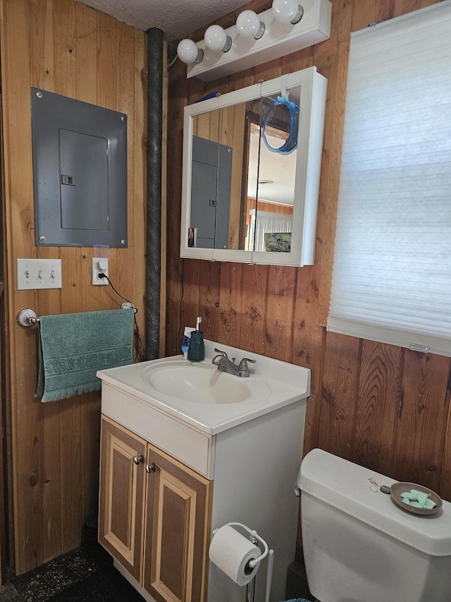 half bath with electric panel, wooden walls, toilet, and vanity