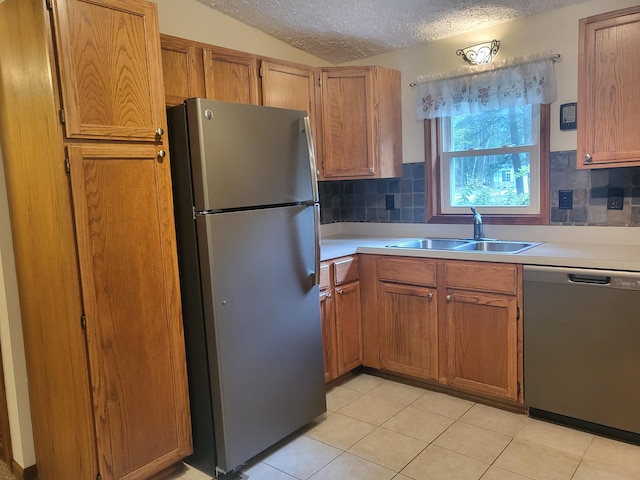 kitchen with a textured ceiling, light countertops, appliances with stainless steel finishes, and a sink