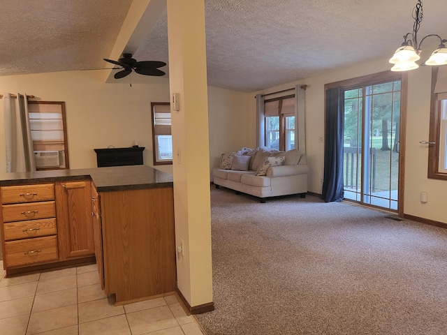 kitchen with dark countertops, open floor plan, light carpet, light tile patterned flooring, and a textured ceiling