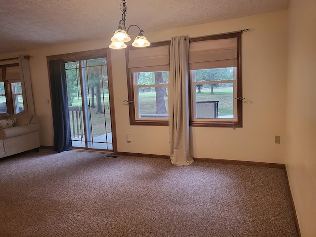 unfurnished room with a chandelier, carpet flooring, a textured ceiling, and baseboards