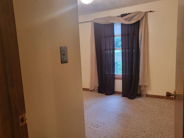 unfurnished room featuring baseboards, a textured ceiling, and carpet