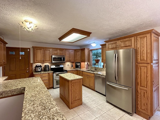 kitchen with a sink, tasteful backsplash, appliances with stainless steel finishes, and brown cabinetry