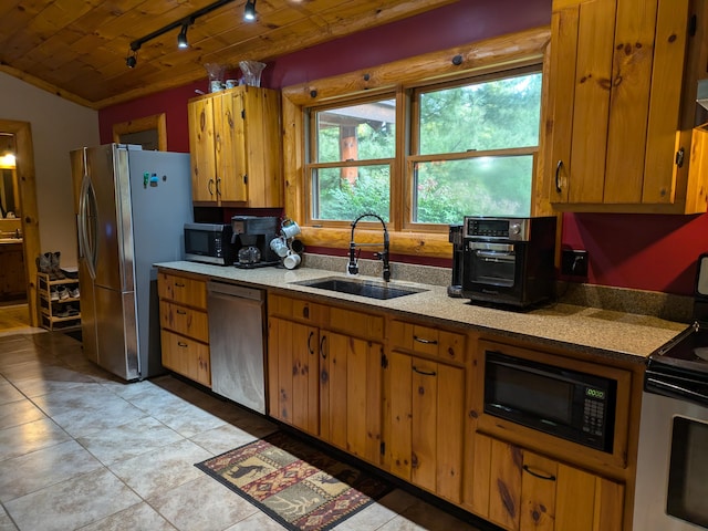 kitchen with light tile patterned floors, brown cabinetry, a sink, light countertops, and appliances with stainless steel finishes