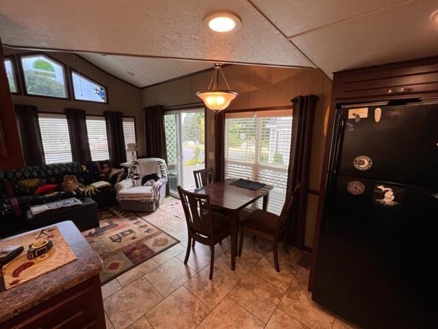 dining area featuring light tile patterned flooring and vaulted ceiling