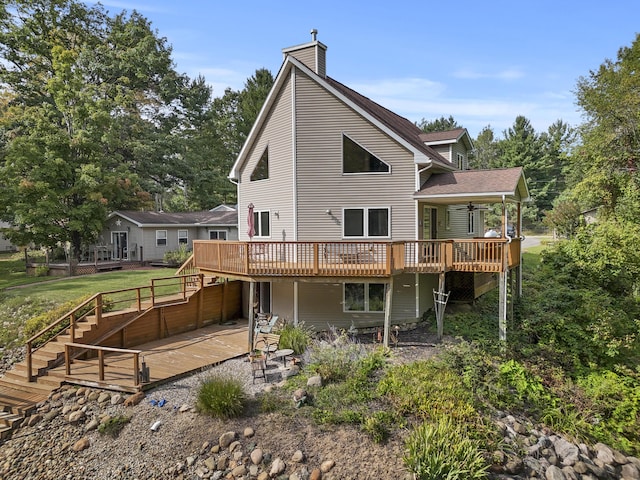 rear view of property featuring a deck, stairway, a lawn, and a chimney