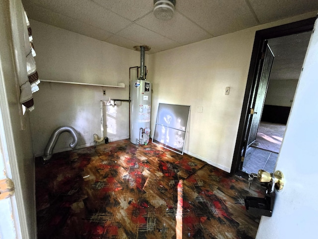 interior space featuring water heater and a drop ceiling