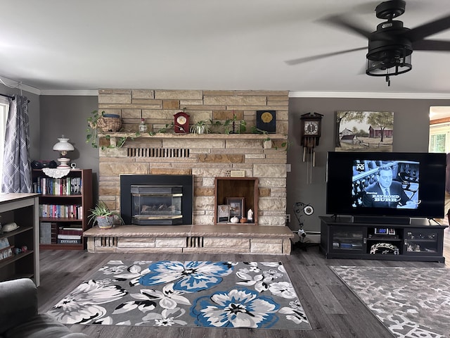 living area with a stone fireplace, crown molding, wood finished floors, and ceiling fan