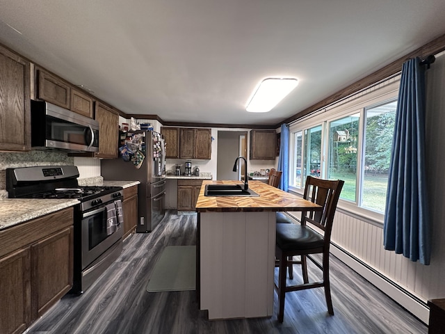 kitchen featuring dark wood-style floors, a sink, appliances with stainless steel finishes, a baseboard heating unit, and butcher block counters