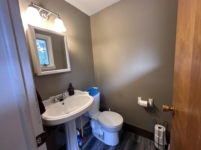 half bath featuring toilet, baseboards, and wood finished floors