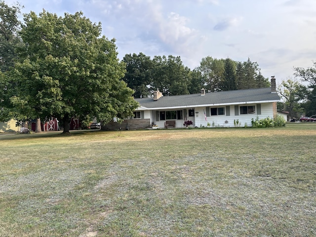 ranch-style house with a chimney and a front lawn