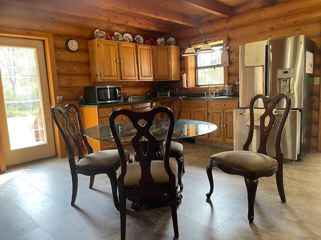 dining area featuring beamed ceiling, log walls, and wood ceiling