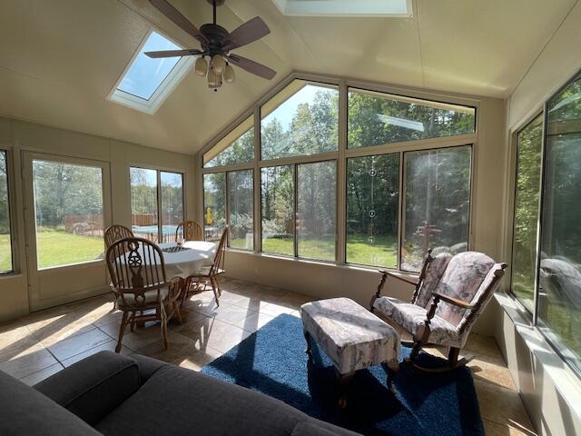 sunroom with lofted ceiling with skylight and a ceiling fan