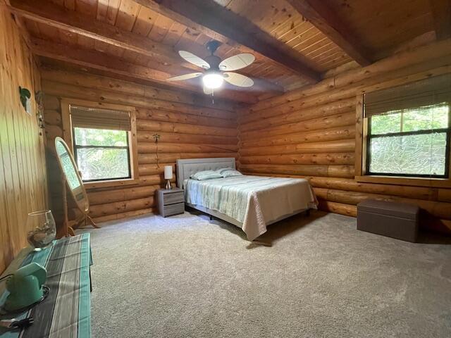 unfurnished bedroom with rustic walls, beam ceiling, carpet floors, and wood ceiling