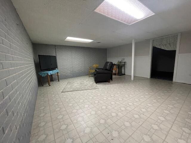 living area featuring tile patterned floors and brick wall