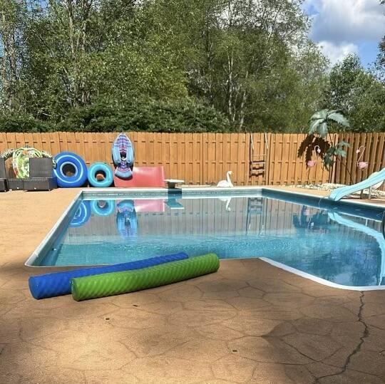 view of swimming pool featuring a patio, fence, a diving board, and a water slide