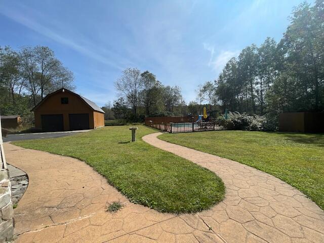 view of yard featuring an outbuilding, a playground, fence, and a detached garage