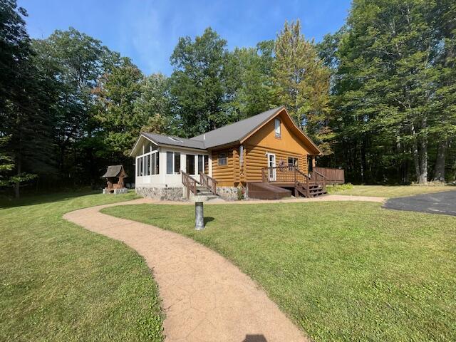 back of house featuring log siding, a lawn, and a deck