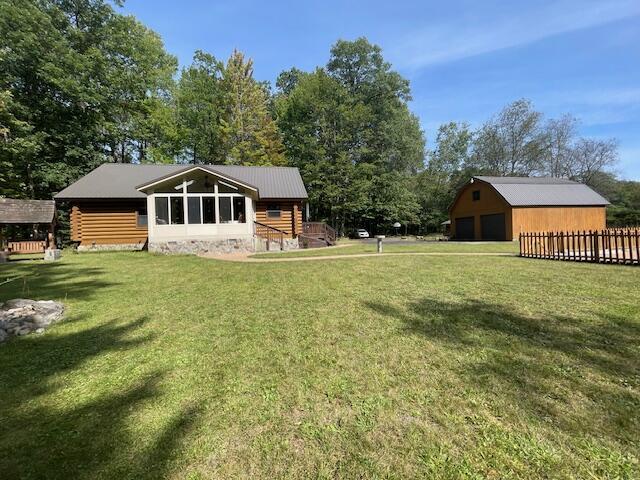 view of yard with a detached garage, an outdoor structure, and fence