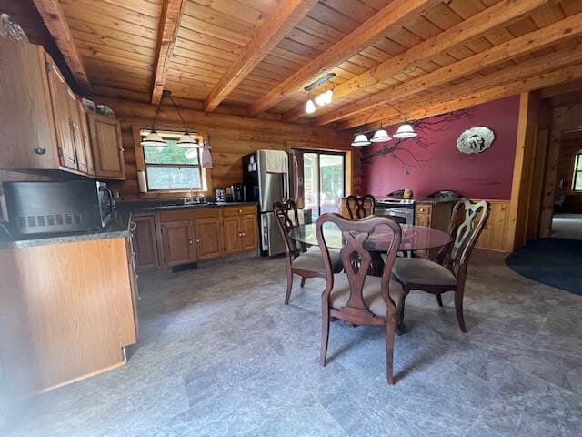 dining space featuring beamed ceiling, plenty of natural light, wooden walls, and wooden ceiling