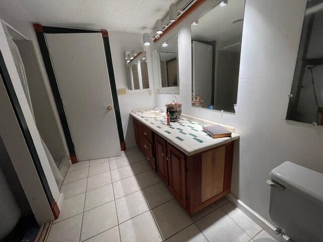 bathroom featuring tile patterned flooring, a textured ceiling, toilet, and vanity