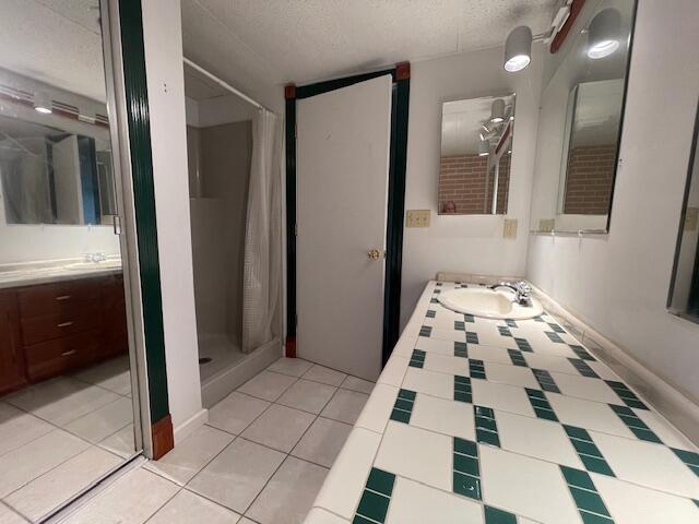 full bath featuring tile patterned floors, vanity, a textured ceiling, and a shower stall