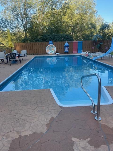 view of swimming pool with a fenced in pool, a patio, a water slide, and a fenced backyard