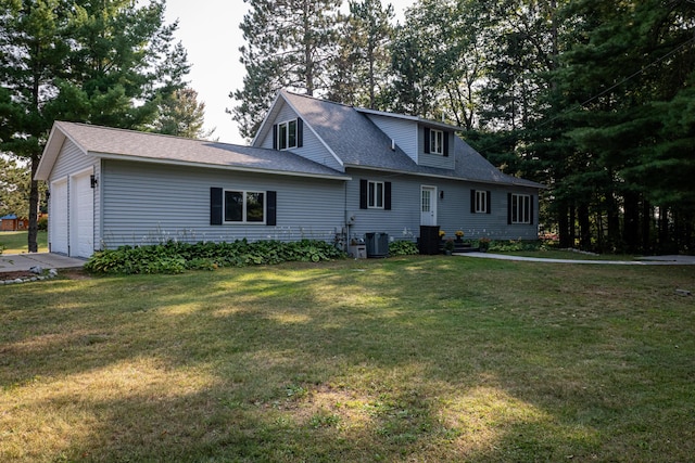 view of front facade featuring central AC unit, an attached garage, and a front yard