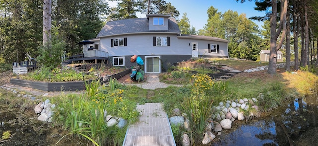 back of property with a wooden deck and a vegetable garden