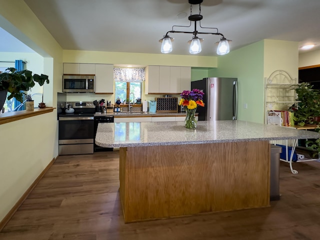 kitchen featuring a center island, pendant lighting, appliances with stainless steel finishes, white cabinetry, and a sink