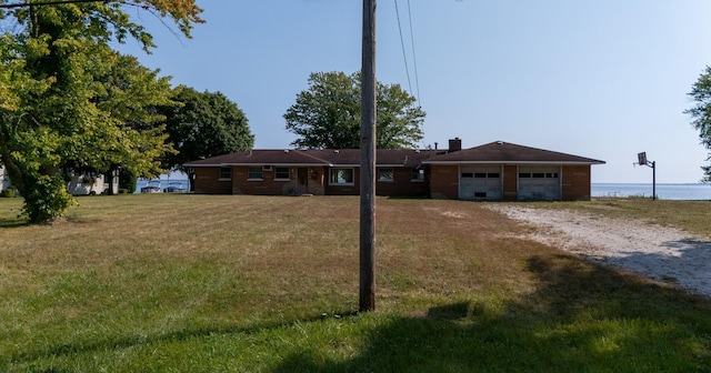 single story home featuring driveway, a chimney, and a front yard