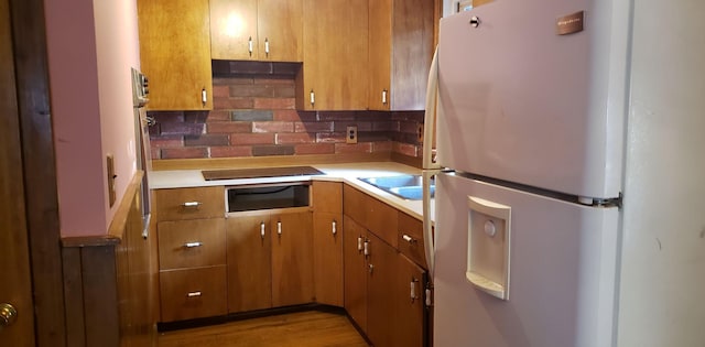 kitchen featuring tasteful backsplash, light countertops, and freestanding refrigerator