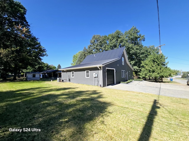 exterior space featuring a yard, a garage, driveway, and metal roof