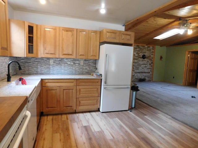 kitchen featuring glass insert cabinets, decorative backsplash, light wood-style flooring, freestanding refrigerator, and a sink