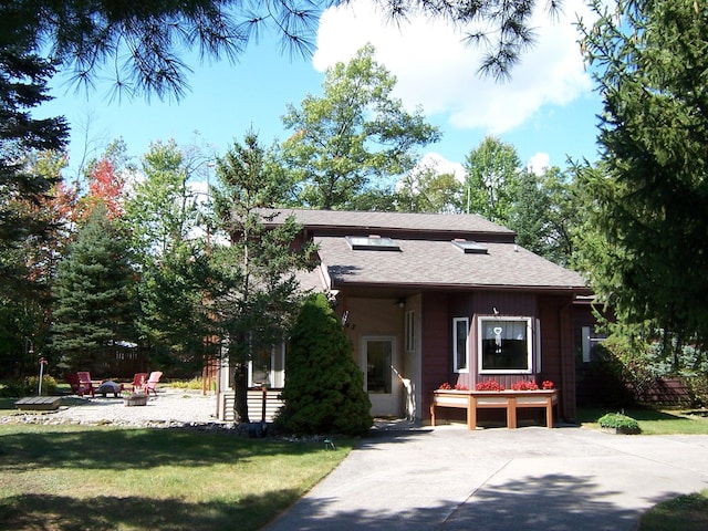 view of front of home with a shingled roof, a front lawn, and an outdoor fire pit