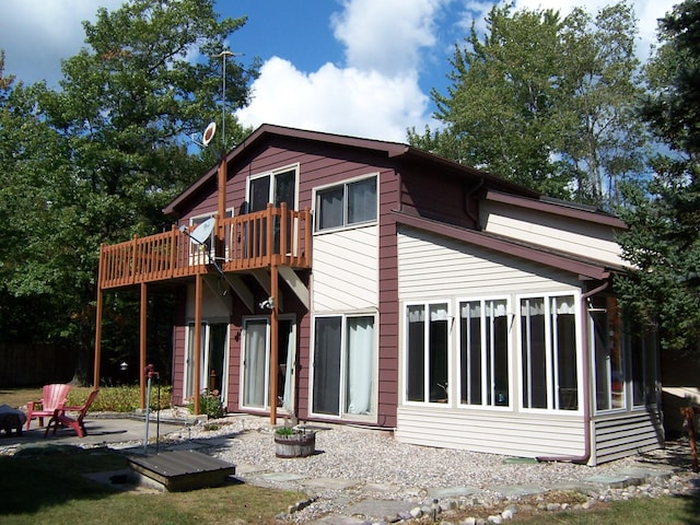 back of property featuring a sunroom and a wooden deck